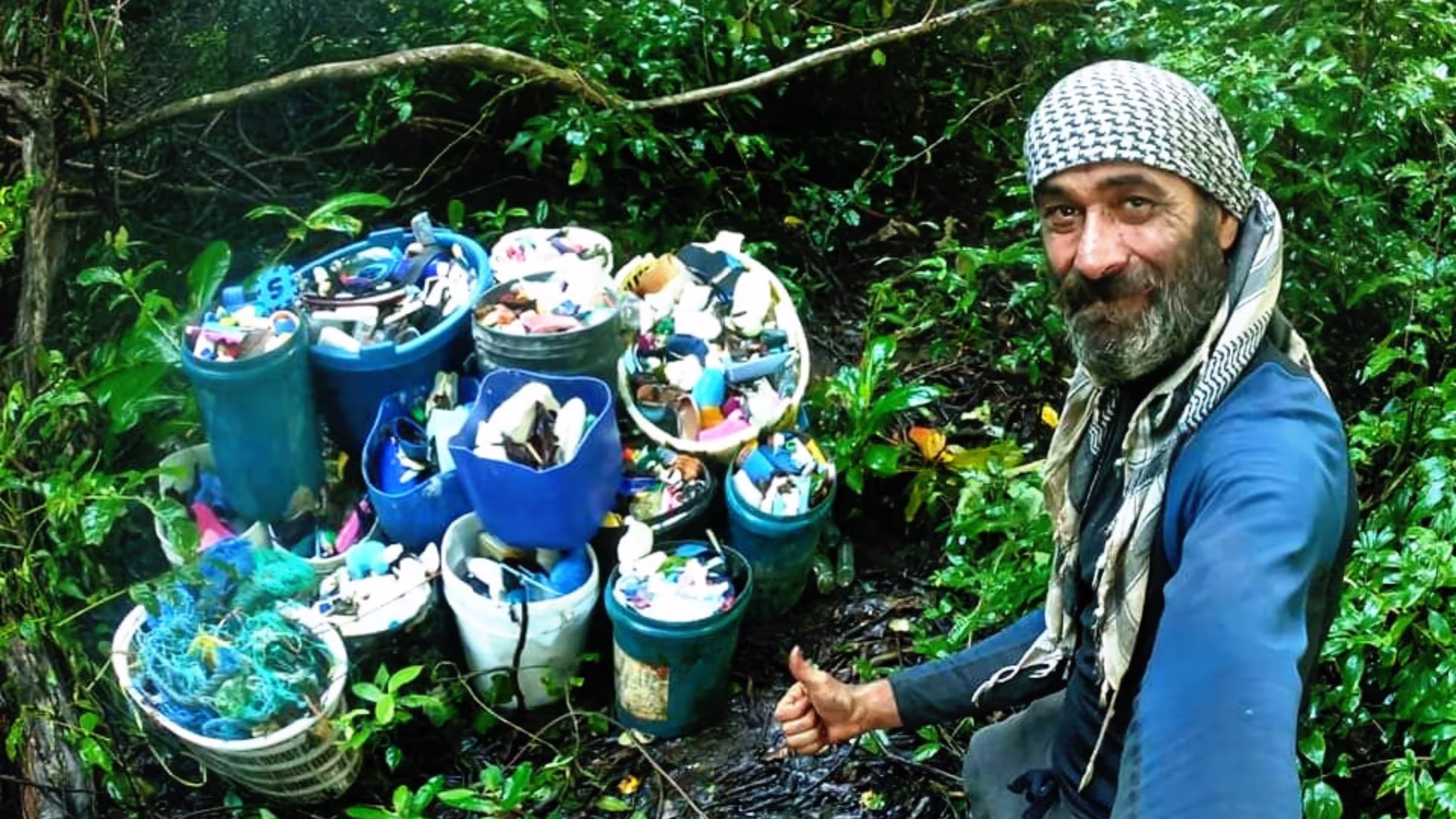 Un homme debout à coté d'une grosse pile de déchets qu'il a ramassé